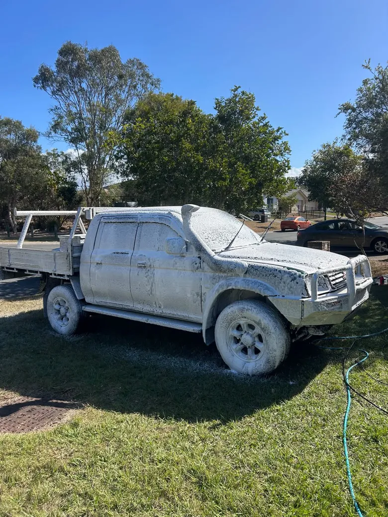 Dual-cab ute covered in snow foam during a hand wash